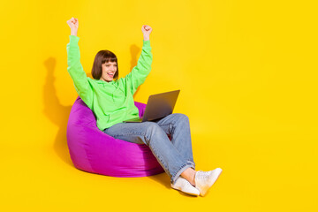 Portrait of attractive cheerful girl using laptop having fun rejoicing isolated over bright yellow color background