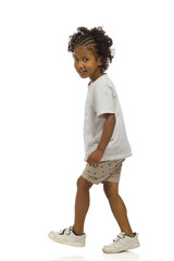 Small black boy in shorts and shirt is walking and looking at camera. Side view. Full length, isolated. - 462175271