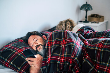 Mature man using mobile phone by woman on bed