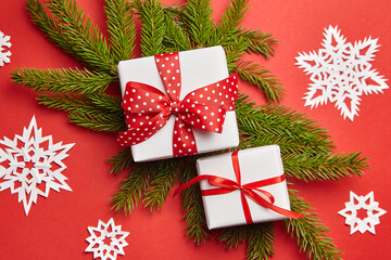 Gift box with Christmas tree branch and white snowflakes on red