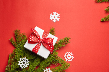 Gift box with Christmas tree branch and white snowflakes on red