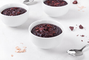 Baked oats with chocolate and cocoa in portion cup on the white table. Porridge variation for breakfast