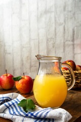 Frischer Apfelsaft in einem Glaskrug und rote Äpfel in einem Korb. Stillleben, gesundes Frühstück.