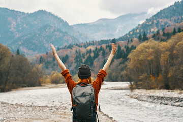 woman hiker near the river with hands raised up mountains landscape