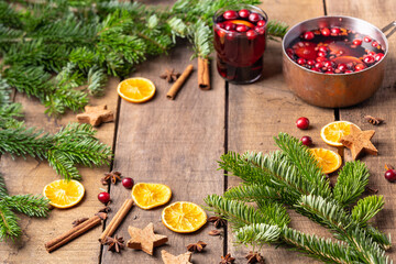 Hot mulled wine made of red wine, berries and oranges. Frame of Christmas tree branches, decoration for New Year and Christmas