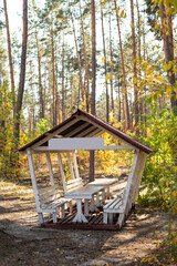 Wooden Gazebo with a Table and Benches for Relaxation and Picnic on a Weekend in Nature Outdoors Forest in Autumn
