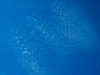 Fototapeta na wymiar Clear blue sky background with small white clouds.