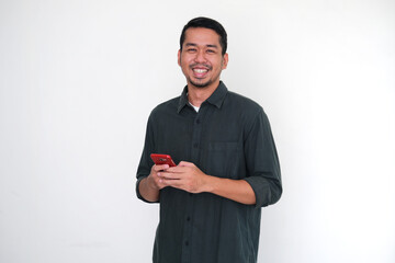 Adult Asian man showing happy face expression when holding his mobile phone