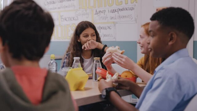 Children having lunch at school canteen, talking and laughing. Kids eating at modern and bright canteen. High quality 4k footage