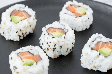 Salmon and avocado sushi pieces on a black plate
