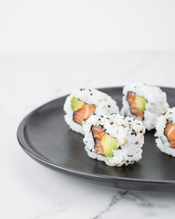 Salmon and avocado sushi pieces on a black plate