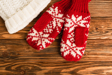 red mittens in ornament near white hat on wooden surface