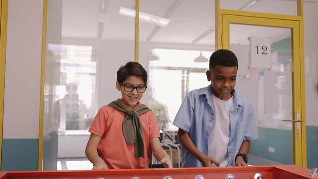 Children playing table football at break in school jumping for joy of winning. Middle school children playing foosball. Kids jumping for joy. Different kids playing together. High quality 4k footage