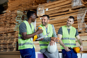 Happy manager and male workers talk and have fun on coffee break at distribution warehouse.