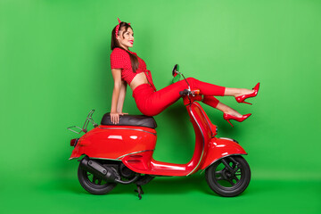 Fototapeta na wymiar Full length body size photo smiling woman in red clothes sitting on motorbike isolated vibrant green color background
