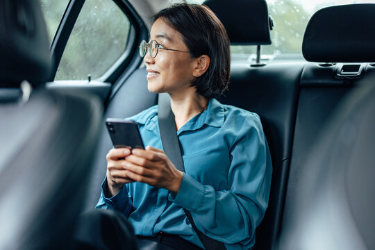 Mature Asian Woman Looking Through Window While Traveling To Work By Car.