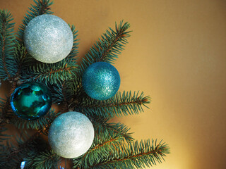 blue and gray shiny Christmas balls lie on a branch of a blue Christmas tree with a garland on a beige background. top view. Christmas