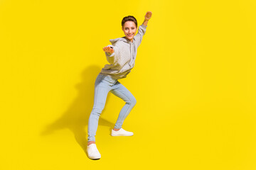 Fototapeta na wymiar Full size photo of cool brown hair millennial lady fight wear sportcloth jeans sneakers isolated on yellow background