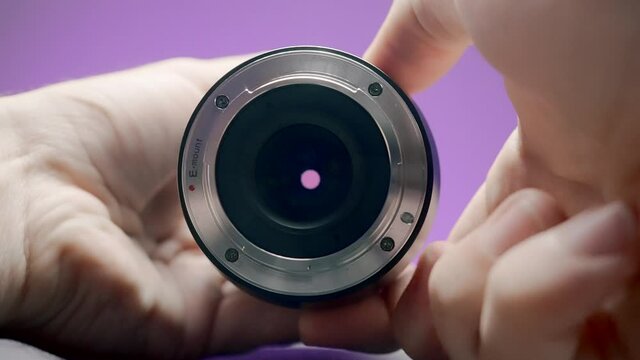 Close-up of man rotating lens. Action. Photographer turns ring of professional lens on isolated background. Lens of lens changes size from rotation of ring by photographer