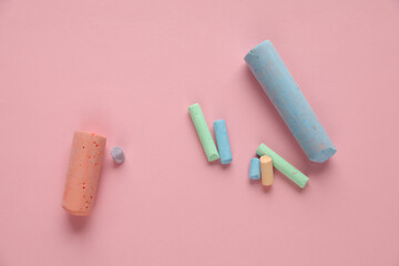 Colored pieces of chalk on a pink background. Crayons for drawing and creativity for children