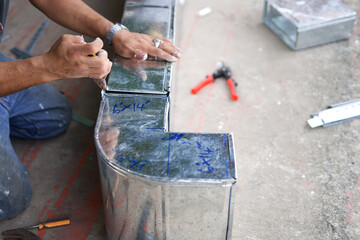 A worker is assembling a plugged-in air duct.
