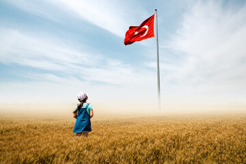 Adorable baby girl is in a field with fog and looking to Turkish national flag admiringly. - 462186822