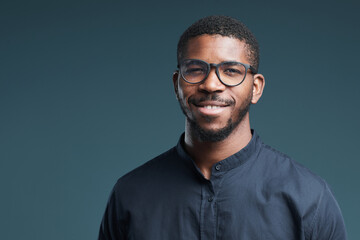 Portrait of handsome African-American man wearing glasses and looking at camera smiling while...