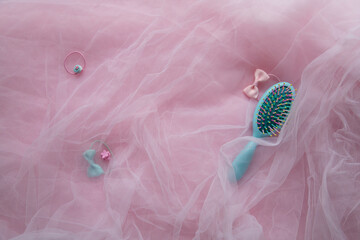 Hair accessories. Blue brush and pink hair bands on a background of pink fabric