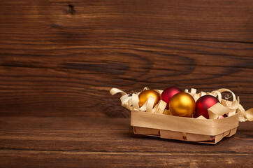 christmas balls in a wicker box on a wooden background