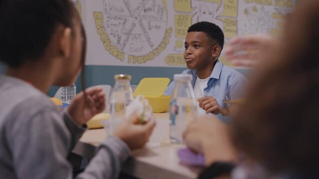 Children having lunch at school canteen, talking and laughing. Kids eating at modern and bright canteen. High quality 4k footage