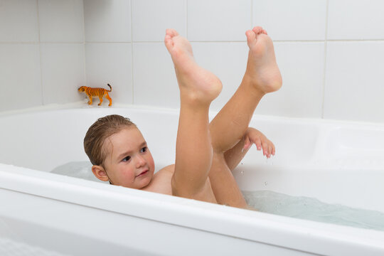 Adorable chubby wet toddler girl splashing around in her bathtub