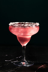 Alcoholic or non-alcoholic rosemary cocktail such as margarita, cosmopolitan or similar on a dark marble table