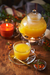 Glass teapot and sea buckthorn tea cup on wooden background