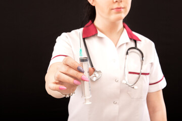 closeup of female nurse with stethoscope and syringe over dark background, vaccination concept