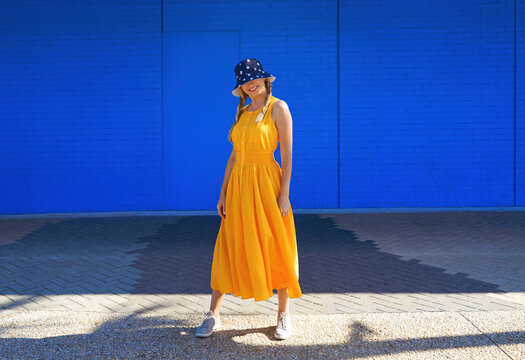 Mature woman wearing bucket hat standing in front of wall on sunny day