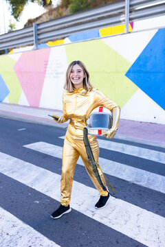 Smiling young woman in astronaut costume crossing street