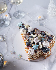 Christmas fruit cake decorated meringue, gingerbread cookies, snowflakes, blueberry. Vertical