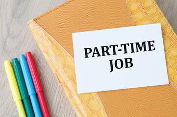 Notepad with a card with text PART TIME JOB on a light wooden background