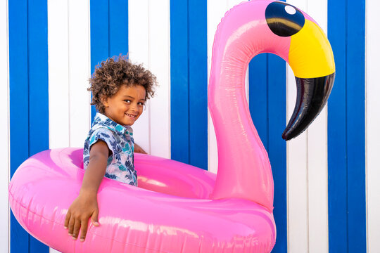 Cute boy playing with inflatable pink flamingo