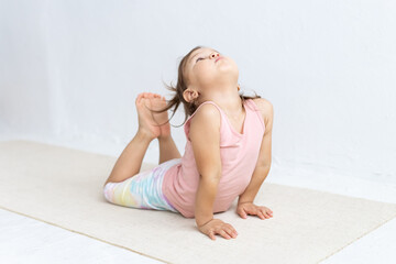 Little mixed race girl practices yoga on floor. Children's yoga. Cobra pose.