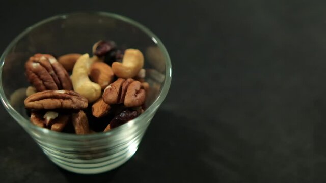 Cup of walnuts, almonds, and Indian nuts on black surface