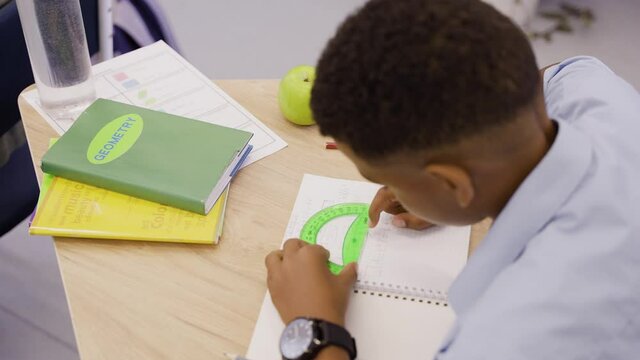 Careful boy drawing in geometry lesson with protractor, ruler and pencil. Clever young boy studying geometry in middle school.High quality 4k footage