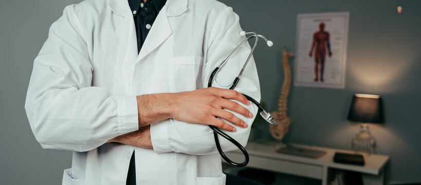 Close up caucasian male doctor working in office standing with arms crossed
