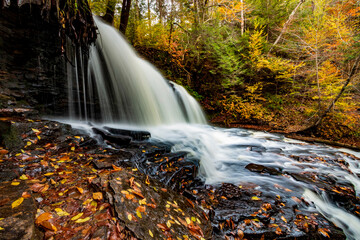 flowing silky cascading waters with  colorful autumn foliage background  on the  woods in Ricketts Glen Pennsylvania
