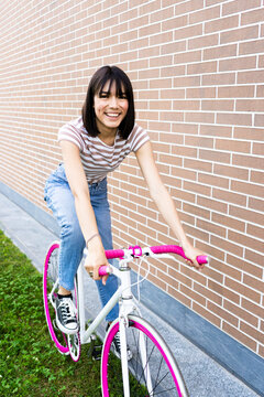 Beautiful woman cycling by wall