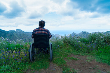 Disabled handicapped woman in wheelchair on mountain hill enjoying view