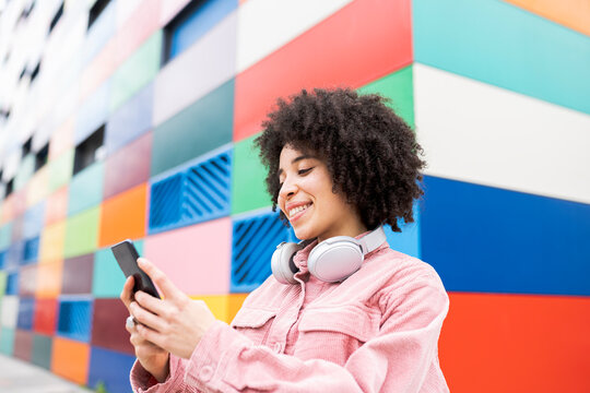 Smiling woman with headphones using mobile phone