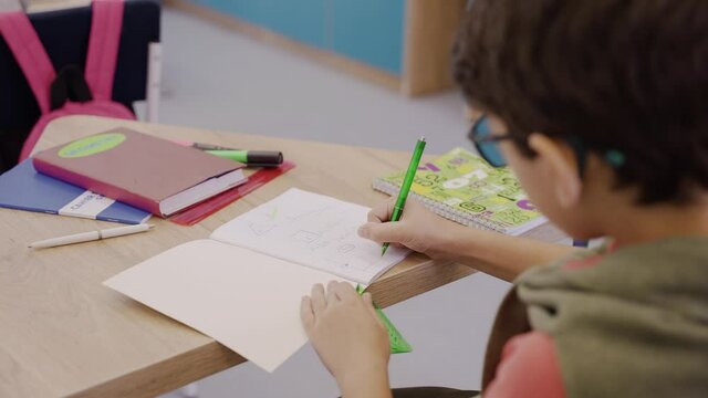 Careful boy drawing in geometry lesson with protractor, ruler and pencil. Clever young boy studying geometry in elementary school.High quality 4k footage