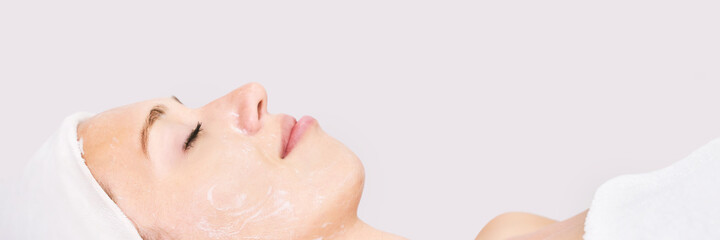 Naklejka premium Face massage at spa salon. Doctor hands. Closeup view. High quality photo. Pretty female patient. Beauty treatment. Healthy skin procedure. Young woman head. Light background. Scrub rejuvenation
