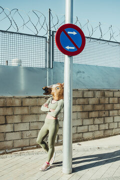 Woman in horse mask leaning on pole